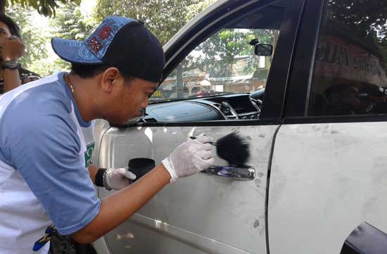 SELIDIKI. Salah satu anggota tim identifikasi Polres Bojonegoro sedang mencari bukti untuk menyelidiki pelaku pemecah kaca milik Pak Haji. Foto: Eky Nurhadi/BANGSAONLINE