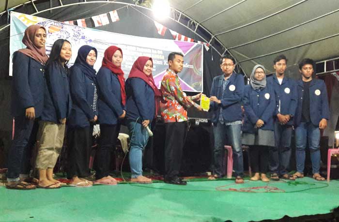 Ketua KKN-BMM Tematik ke-56 Unair Thaariq Ilham didampingi anggotanya saat menyerahkan cindera mata kepada Kades Pejok Mustahar. foto: SYUHUD/ BANGSAONLINE