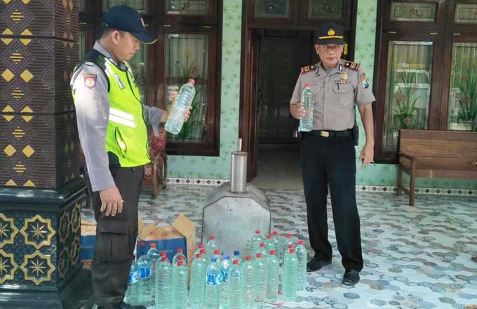 Petugas saat mengamankan miras jenis arak dari rumah STM. foto: SUWANDI/ BANGSAONLINE