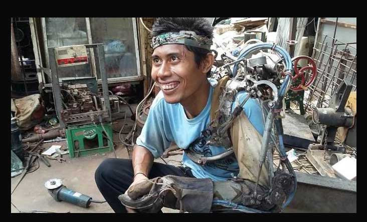 Tawan alias I Wayan Sumardana mengenakan tangan robot ciptaanya di bengkel miliknya.