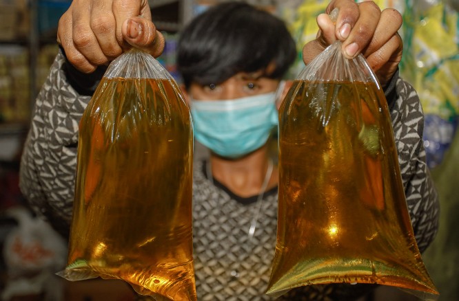 ILUSTRASI. Seorang penjual minyak goreng curah di Surabaya menunjukkan dagangannya. Foto: Jawa Pos
