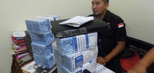 Petugas saat menginterogasi tersangka. Tampak barang bukti berupa uang tunai senilai Rp 400 Juta. foto: zainal/ BANGSAONLINE