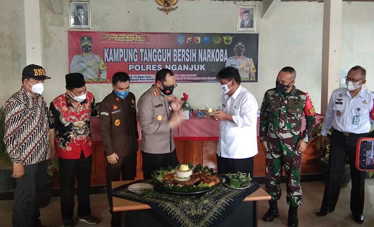 Plt Bupati Nganjuk Marhaen Jumadi menerima potongan tumpeng dari Kapolres Nganjuk AKBP Harviandhi saat peresmian Desa Tanjungrejo sebagai Kampung Tangguh Bersih Narkoba. foto: BAMBANG/ BANGSAONLINE