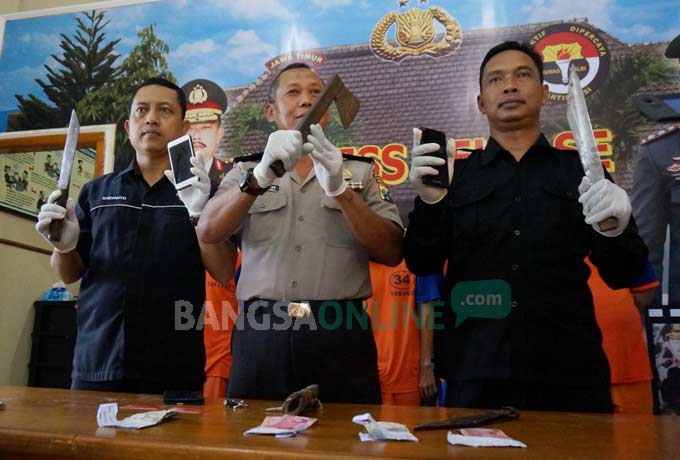 Petugas menunjukkan kapak dan pisau tajam yang digunakan pelaku begal. foto : RONY S/ BANGSAONLINE