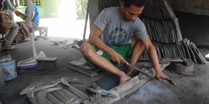 Gufron saat mengerjakan pesanan Golok milik pelanggan. (foto: rony suhartomo/BANGSAONLINE)