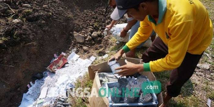 Petugas saat memasukkan ribuan petasan ke kubangan raksasa di TPA Gedangkeret. foto: RONY S/ BANGSAONLINE