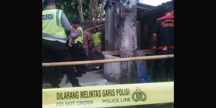 Petugas memasang garis polisi di lokasi dekat sumur yang menewaskan dua orang pekerja. foto: BANGSAONLINE