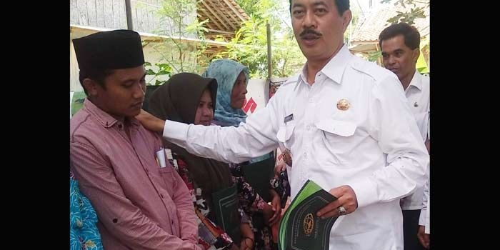 Pj Bupati Pamekasan Fattah Jasin ketika menyerahkan sertifikat yang sudah jadi pada warga Pamekasan.