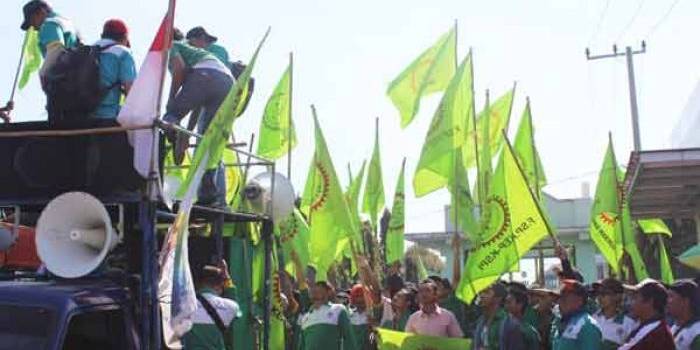 BERTAHAN.  Ratusan buruh yang menuntut rekannya dipekerjakan kembali dengan mendirikan tenda di depan pabrik, kemarin. foto: khumaidi/BANGSAONLINE