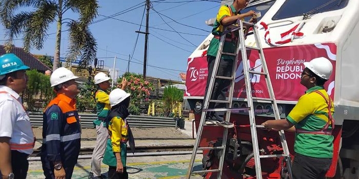 Kepala Daerah Operasi PT PT KAI Daop 7 Madiun, Suharjono, memeriksa pelaksanaan menghias lokomotif. Foto: HENDRO SUHARTONO/ BANGSAONLINE