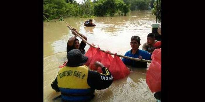 Tim tanggap darurat Dinsos dan BPBD membantu mengevakasi dan memberikan nasi bungkus kepada korban banjir. foto: bahri/ BANGSAONLINE