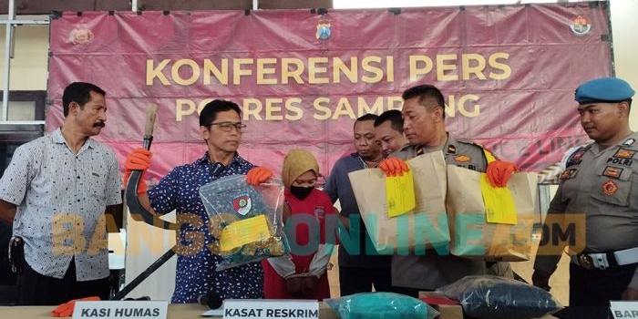 Petugas Polres Sampang menunjukkan celurit dan pakaian yang digunakan tersangka saat melakukan pembunuhan. Foto: MUTAMMIM/ BANGSAONLINE
