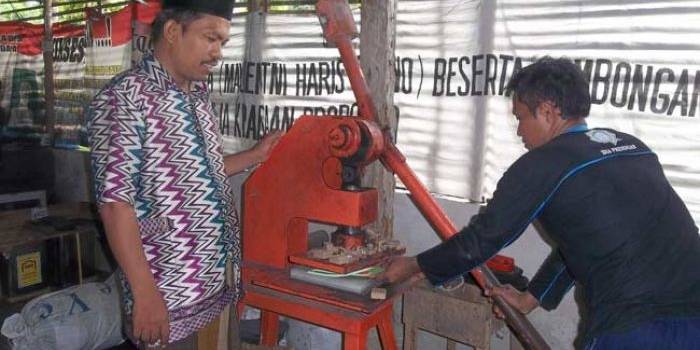 Haruji (berpeci) saat mengawasi karyawannya bekerja. foto: RAHMATULLAH/ BANGSAONLINE