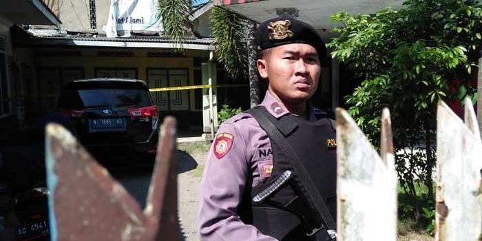 Petugas berjaga di depan rumah kontrakan NH yang baru saja digerebek. foto: AKINA/ BANGSAONLINE