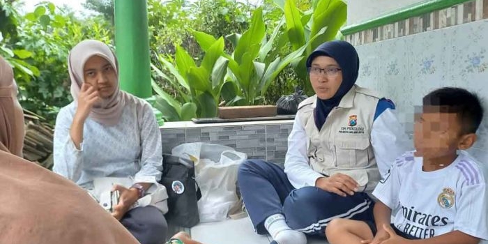 Petugas dari Satgas Polresta Malang Kota bagian Trauma Healing saat memberi bantuan psikologis kepada seorang bocah laki-laki berinisal P (7 tahun) dari Kelurahan Tlogowaru, Kecamatan Kedungkandang.