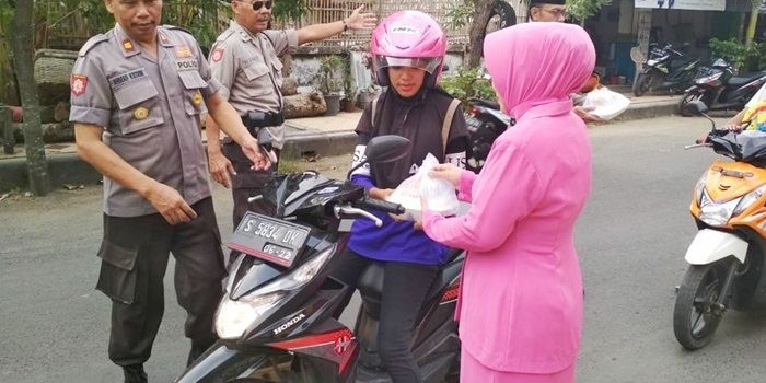 Petugas Polsek Senori bersama istri saat berbagi takjil kepada pengguna jalan. 