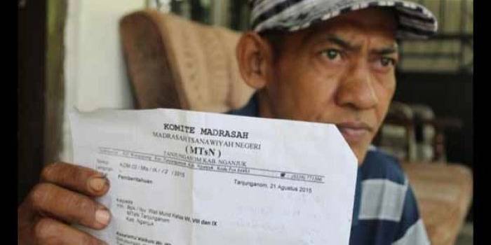 Salah seorang wali murid menunjukan surat edaran sari MTsN 1 Tanjunganom Nganjuk. foto: soewandito/BANGSAONLINE