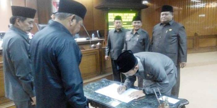 TEKEN: Ketua DPRD Sidoarjo H Sullamul Hadi Nurmawan meneken berita acara pengesahan lima Perda tentang Desa disaksikan Bupati H Saiful Ilah, saat rapat Paripurna, Kamis (23/6) petang. foto: MUSTAIN/ BANGSAONLINE