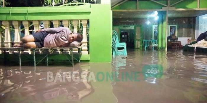 Warga terpaksa tidur di teras rumah karena kebanjiran, sambil menunggu air surut. foto: rony suhartomo/ BANGSAONLINE