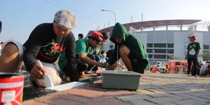 Para Bonek sedang sibuk mengecat paving sekitar GBT.