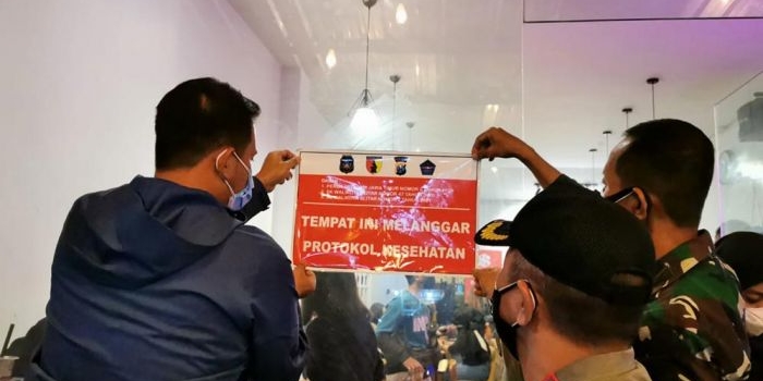 Petugas memasang stiker peringatan di kafe-kafe yang kedapatan melanggar protokol kesehatan. 