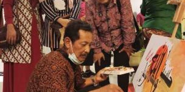 Drs. Romadlon Sukardi (jongkok pakai kopiah hitam) menyaksikan salah satu seniman yang sedang mendemonstrasikan kebolehannya dalam melukis. foto: ist