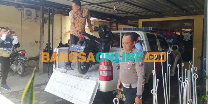 Petugas dari Satlantas Polres Sampang saat mengevakuasi kendaraan roda dua yang terlibat kecelakaan dengan truk muatan besi cor. Foto: MUTAMMIM/BANGSAONLINE 