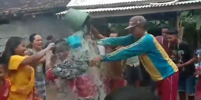 Mukadar saat dimandikan kembang dan ditaburi tepung oleh para tetangganya saat pulang dari karantina.