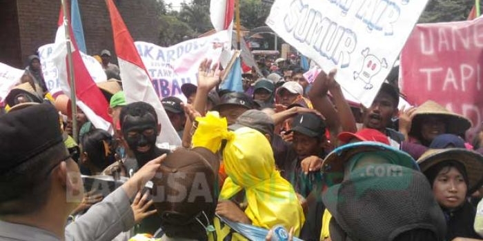 Seorang peserta aksi dengan kostum pocong terjebak rekannya ketika aksi sempat memanas. Aksi di depan Pemkab Mojokerto ini mendapat penjagaan ketat dari polisi. foto: YUDI EP/ BANGSAONLINE