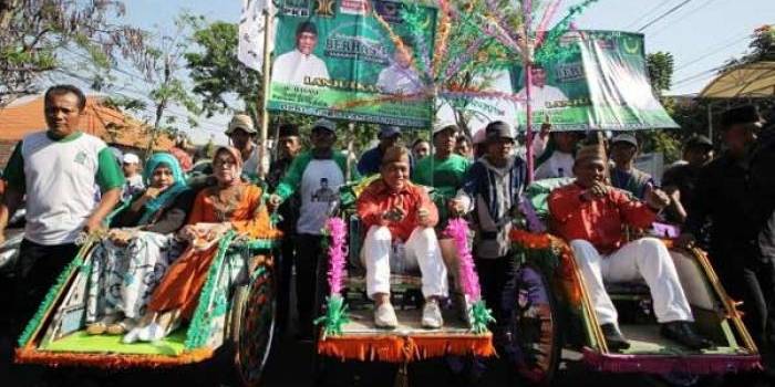 Bakal calon Wali Kota Pasuruan Hasani (tengah) dan wakilnya Muhammad Yasin (kanan) naik becak saat akan mendaftar ke kantor Komisi Pemilihan Umum (KPU) Kota Pasuruan beberapa waktu lalu.
