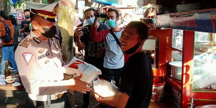 Petugas kepolisian saat membagikan sembako pada PKL di Alun-Alun Kota Probolinggo.
