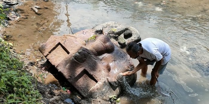 Gunawan saat membersihkan arca berbentuk kala (penthul) yang baru ditemukan di Sungai Penthul Dusun Kranggan, Desa Nambaan, Kecamatan Ngasem, Kabupaten Kediri. Foto: Muji Harjita/ BANGSAONLINE.com