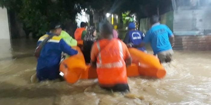 Petugas BPBD dan Tagana mengevakuasi warga beserta barang-barang menggunakan perahu karet.