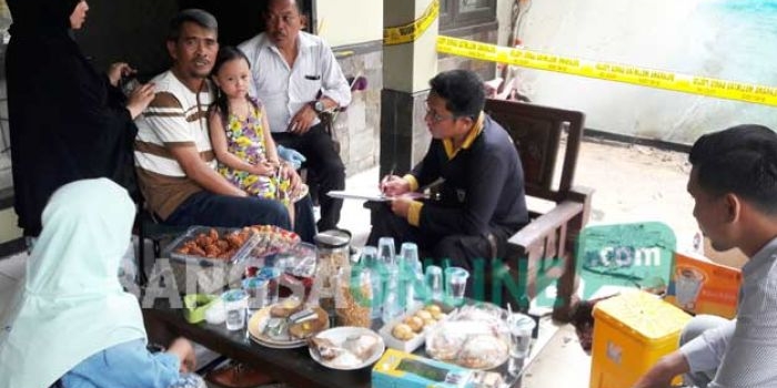 Khamsun (memangku anaknya), didampingi istri ketika dimintai keterangan petugas tim Labfor Polda Jatim. foto: SYUHUD/ BANGSAONLINE