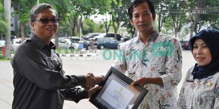 Plt  Sekkab Gresik, ketika memberikan piagam penghargaan kades peduli kesehatan. foto: syuhud/ BANGSAONLINE