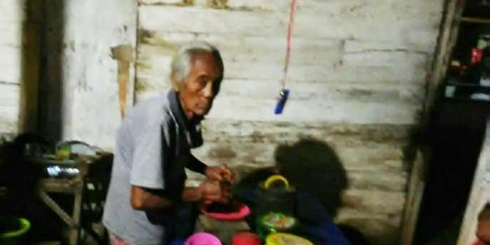 Mbah Nasri tengah menyajikan kopi untuk pelanggan warungnya.