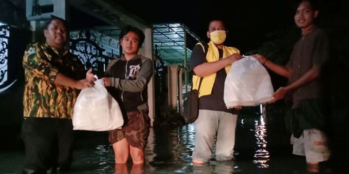 Pengurus DPD Golkar Pasuruan dibantu kader AMPG saat membagikan nasi bungkus ke korban banjir.