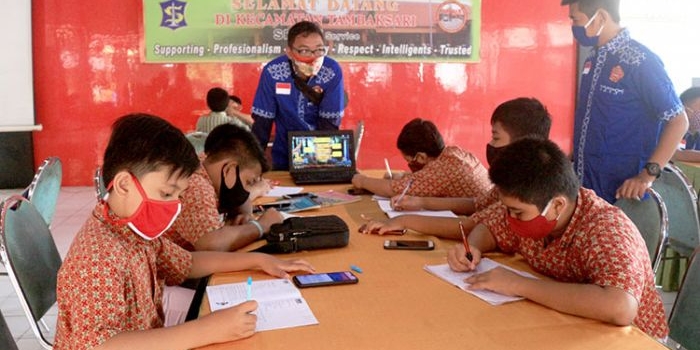 Para pelajar saat sedang belajar secara online didampingi kakak-kakak karang taruna setempat. (foto: ist).