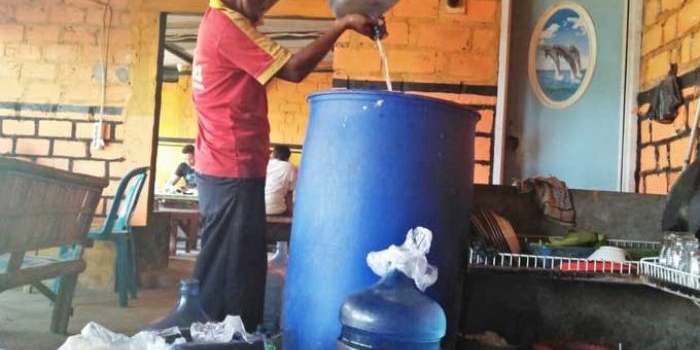 Joni, pemilik warung kopi ini harus mengambil air di desa sebelah agar bisa tetap bisa berjualan. foto: 