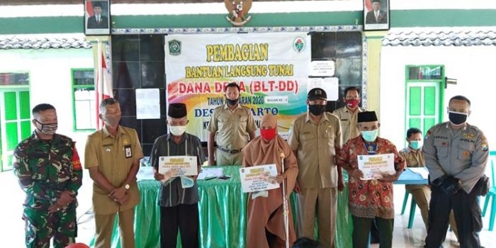 Babinsa Jokarto Koramil 0821/10 Tempeh, Serda Imam Wahyudi saat mendampingi kegiatan penyaluran BLT DD Tahap II yang bertempat di Balai Desa Jokarto, Kecamatan Tempeh, Kabupaten Lumajang, Senin (8/6/2020).