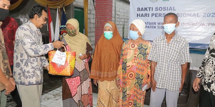 Plt Kepala Diskominfo Sidoarjo, Ahmad Misbahul Munir, saat menyerahkan sembako dalam giat Baksos HPN 2022 PWI Sidoarjo, Selasa (19/4/2022). Foto: Ist