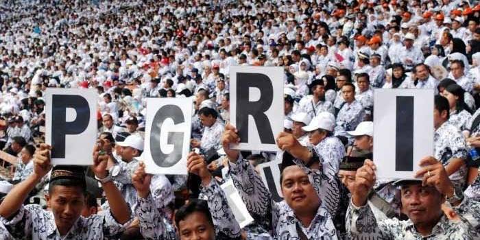 PERINGATI HUT: Sejumlah guru membentangkan poster bertuliskan PGRI saat mengikuti peringatan puncak HUT ke-70 PGRI, di GBK, Jakarta, Minggu (13/12). foto: poskotanews