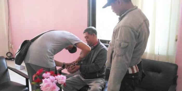 Tersangka Achmad Lukman (duduk) saat diborgol kedua tangannya oleh petugas Kejaksaan. foto: NANANG ICHWAN/ BANGSAONLINE