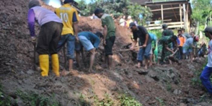 Warga dibantu TNI, Polri, BPBD dan Tagana membersihkan sisa runtuhan tanah yang menutup jalan. (Soewandito/BANGSAONLINE)