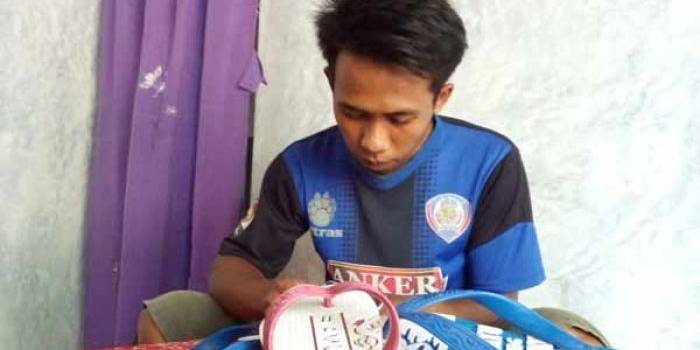 Wahyu saat sedang menggarap sandal jepit karyanya. foto: zainal abidin/BANGSAONLINE