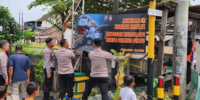 polisi-pasang-spanduk-imbauan-di-perlintasan-kereta-api-tak-berpalang