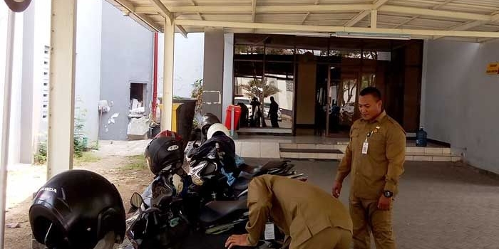 Petugas Dispol PP saat menggembosi ban sepeda motor yang parkir di areal terlarang kantor pemkab.