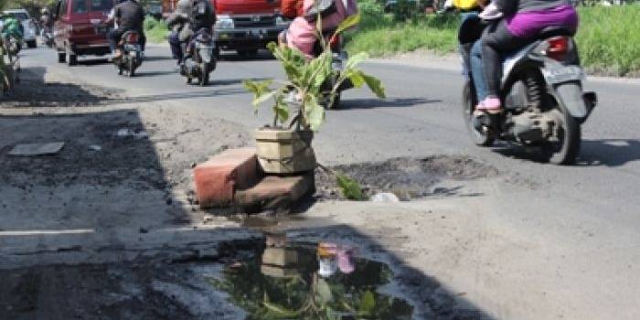 Warga Dusun Banar Desa Pilang Kecamatan Wonoayu meletakan pot bunga tengah jalan sebagai bentuk protes jalan rusak yang tak segera diperbaiki, kemarin. foto : khumaidi/BANGSAONLINE