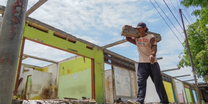 Seorang pekerja saat melewati bangunan pasar Ngadiluwih yang sudah mulai dibongkar. (Ist)