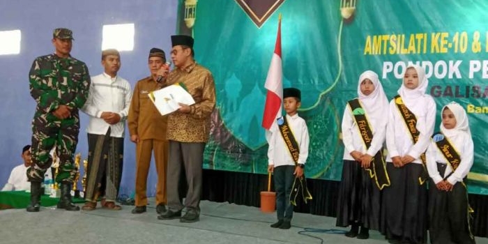 Wakil Ketua IV Baznas Jatim, KH Husnul Khuluq, saat memberikan beasiswa secara simbolis kepada salah satu siswa/santri berprestasi. Foto: Ist